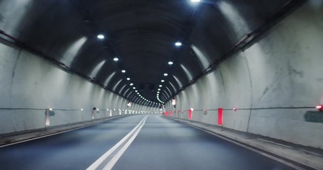 Driving along the modern illumanated empty tunnel on freeway to the big city at night. No people. Night adventure roadtrip.