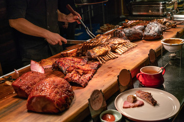 Chef in meat buffet counter cutting delicious grilled ribs 