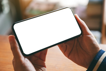 Mockup image of hands holding black mobile phone with blank desktop screen