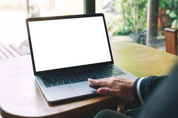 Mockup image of a woman using and touching laptop touchpad with blank white desktop screen on wooden table