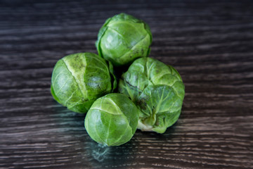 Rustic, organic, healthy brussel sprouts. Home grown and displayed on a dark wood grain bench. Dark green leafy outer, white and creamy inside. Brassica high in vitamins C, B and K, good for winter.