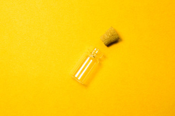 Empty little bottle with cork stopper isolated on yellow. transparent container. test tube