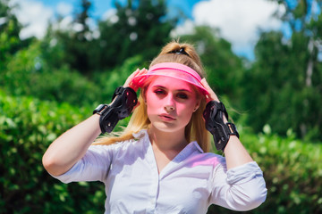 Portrait of an emotional girl in a pink cap visor and protective gloves for rollerblades and...