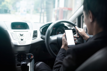 Asian men holding a mobile phone while driving a car.
