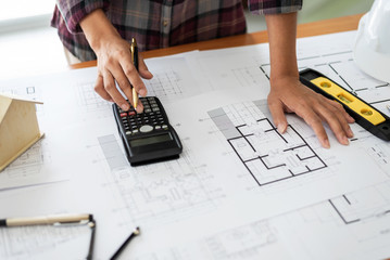 Female architect drawing blueprints in office workplace.