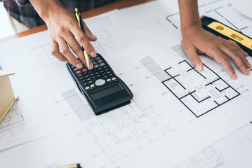 Female architect drawing blueprints in office workplace.