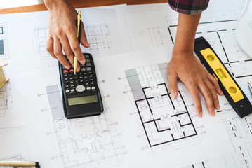 Female architect drawing blueprints in office workplace.