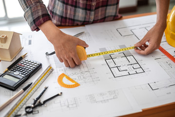 Female architect drawing blueprints in office workplace.