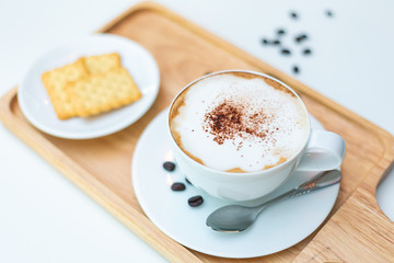 Hot coffee on background served with cream crackers on white plate.