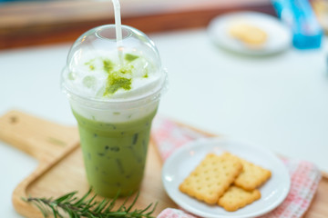 Iced Green tea with cracker on wooden plate.