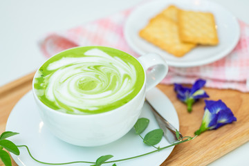 Hot green tea milk with cracker and spoon.