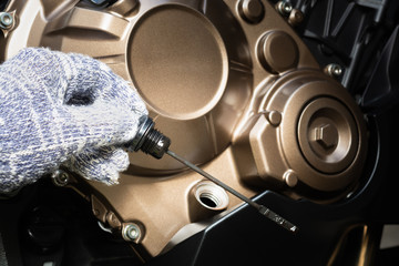 Hand of technician wearing cloth gloves check lubricant engine oil level motorcycle bigbike. maintenance motorcycle concept in garage or check before you travel.