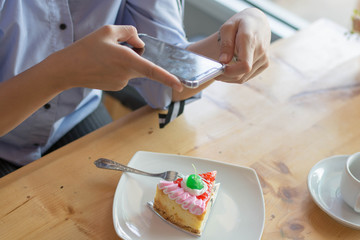 woman taking picture of strawbery cake with smartphone