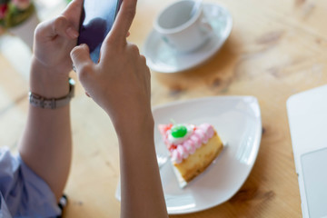 Obraz na płótnie Canvas woman taking picture of strawbery cake with smartphone
