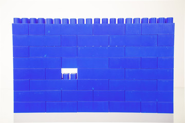 A wall of blue children's colorful plastic building toys bricks, with one missing piece