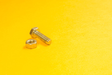 Obraz na płótnie Canvas Steel screw on a yellow background