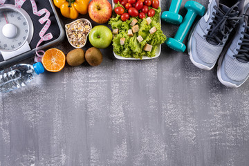 Healthy lifestyle, food and sport concept. Top view of athlete's equipment Weight Scale measuring tape pink dumbbell, sport water bottles, fruit and vegetables on gray background.