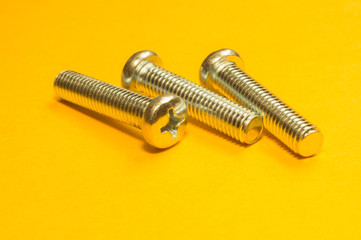 Steel screw on a yellow background