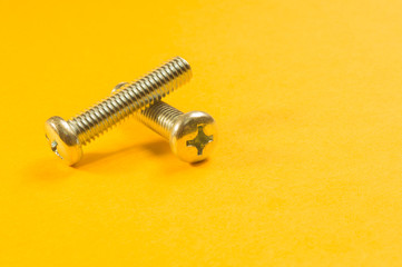 Screws on a yellow background. pile of fasteners