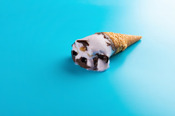side view half melted sweet potato flavor ice cream cone on a blue background