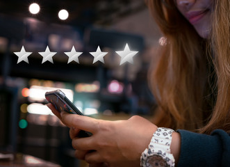 Woman internet shopping on smartphone submitting 5 silver star satisfaction feedback - Millennial...