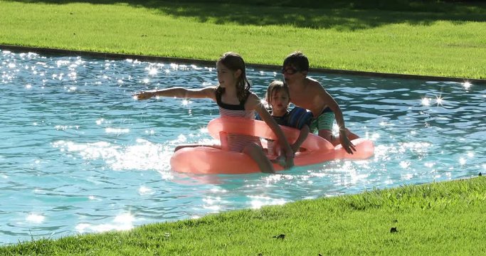 Children playing the swimming pool water on top of inflatable mattress