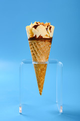 side view mango and chocolate flavor ice cream cone with peanut on blue background