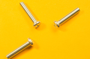 Screws on a yellow background. pile of fasteners