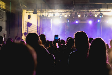 Fototapeta na wymiar Tel Aviv, Israel February 23, 2018: Person taking a picture of a concert with purple fog and a bright stage area