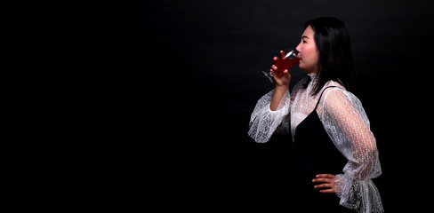 Portrait of beautiful Asian woman holding a glass of champagne, isolated on black background.