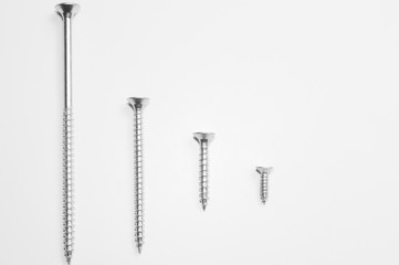 Various screws in a row on a white background