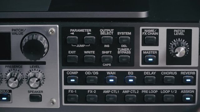 Musician tests the parameters of a preamp guitar multi effect, close up 4K