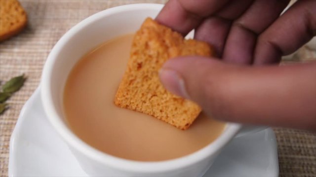 Close and Slow motion shot of a girl dipping crisp rusk in her tea . 