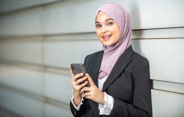 Fototapeta na wymiar Young Female Muslim Entrepreneur looking at her smartphone. Shallow depth of field.