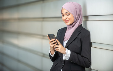 Young Female Muslim Entrepreneur looking at her smartphone. Shallow depth of field.