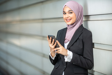 Young Female Muslim Entrepreneur looking at her smartphone. Shallow depth of field.