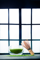 Matcha green tea in a double wall glass tea bowl with a bamboo whisk. Shoji sliding doors background, traditional Japanese ceremony