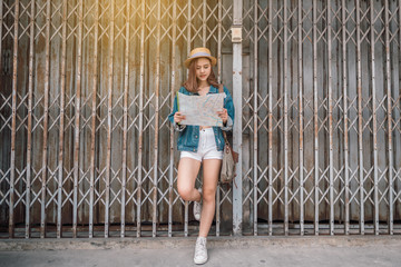 Cheerful traveler woman wanderer with trendy look searching direction on location map