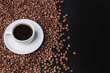 cup of coffee with beans on black background with copy space