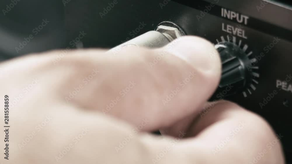 Poster musician plugs in the jack cable into a multi effect and sets up the input level at maximum, macro s