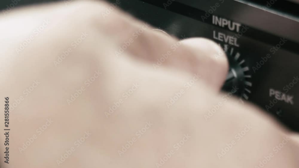 Poster musician plugs in the jack cable into a multi effect and sets up the input level, macro shot.