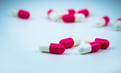 Pink-white capsule pill on blurred capsule background. Antibiotic drug resistance. Antimicrobial capsule pills. Pharmacy drugstore. Pharmaceutical industry. Healthcare medication. Pharmaceutics.