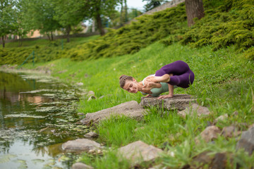 Thin brunette girl plays sports and performs beautiful and sophisticated yoga poses in a summer...