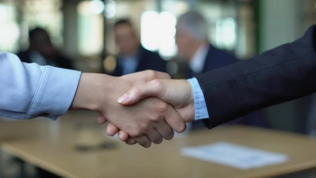 Two women in suit shaking hands, business deal approval, project cooperation