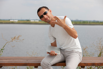 Handsome young man sitting near the sea with a laptop.