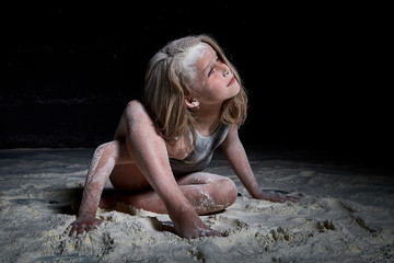 Small girl during photoshoot with flour in dark studio