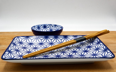 Chinese table set. Wooden chopsticks, chinese bowl and a jar on wooden table, white background