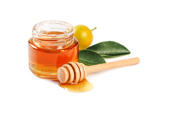 Honey in glass jar with dipper and leaves on white background