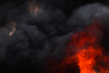 Flames strong red industrial fire, dramatic clouds of black smoke covered sky