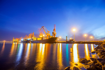 Fototapeta na wymiar Gantry crane and cargo ship in the evening